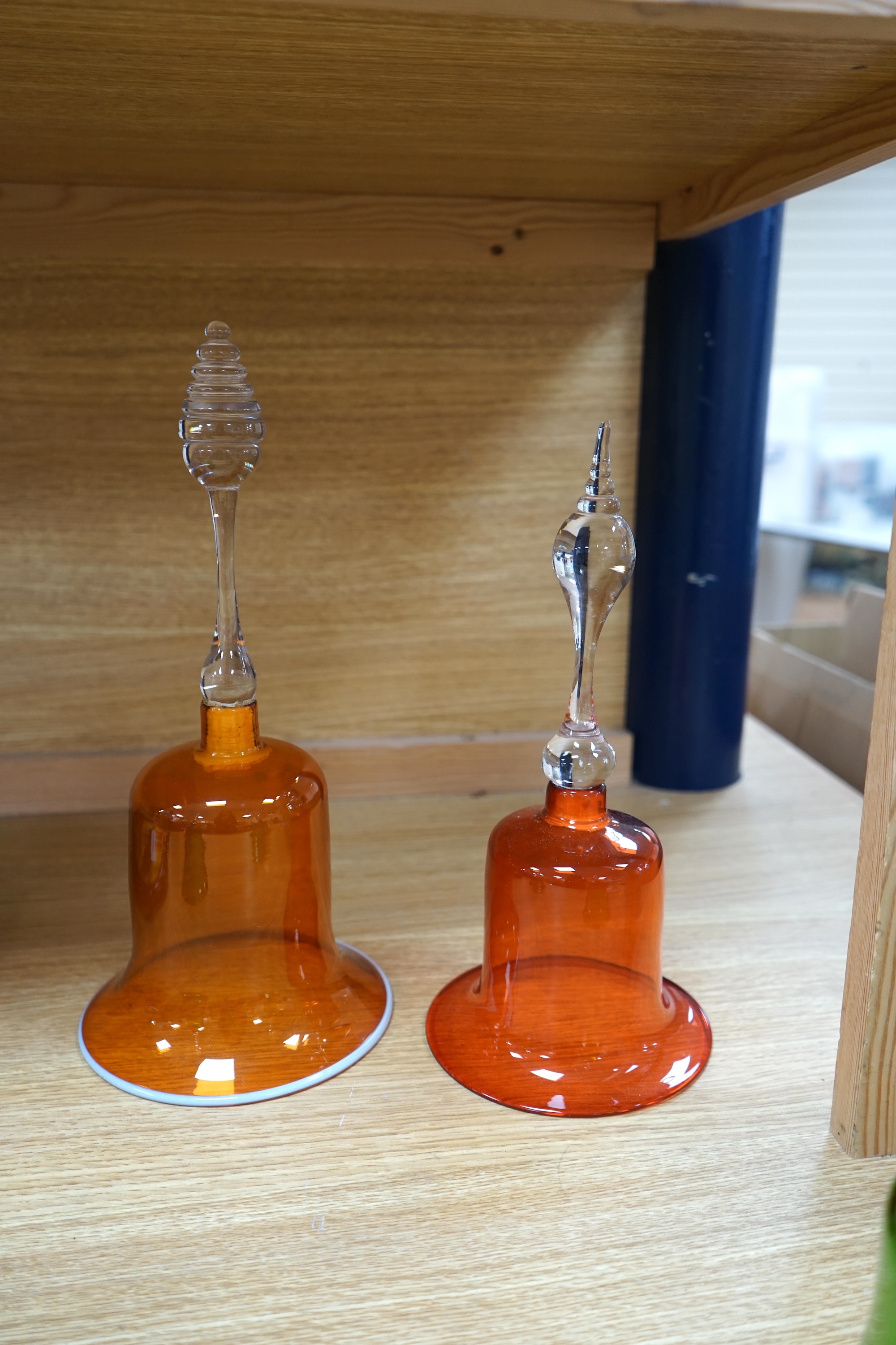 Five hand bells comprising an amber glass example with twist handle, two orange and two green glass hand bells, largest 36cm high. Condition - some repairs